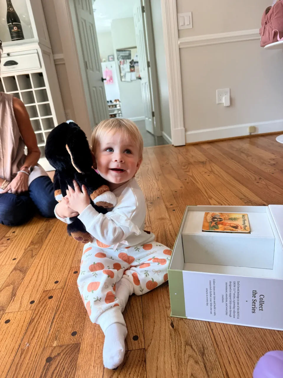 A child hugging the Ollie plush beside the set