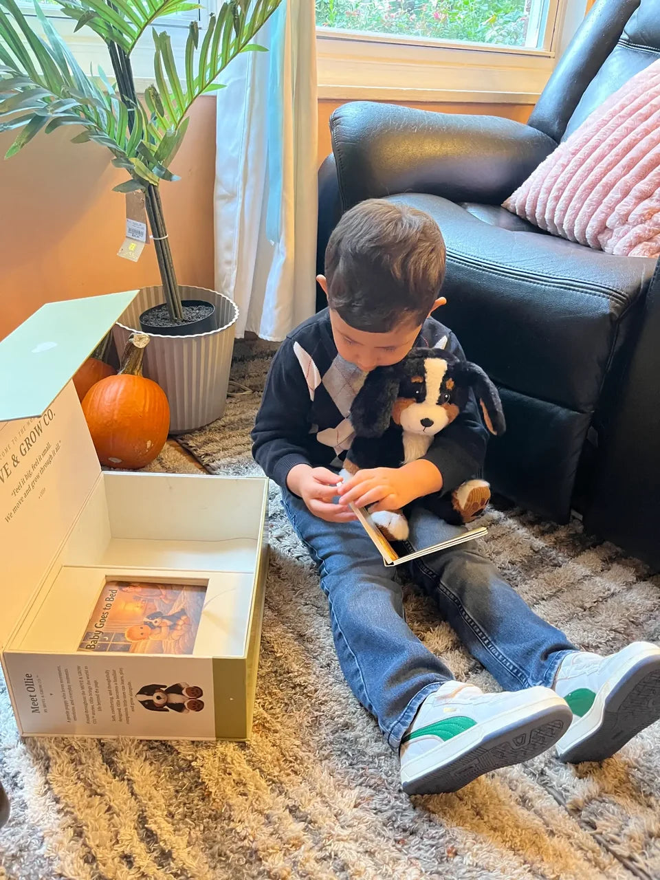 A child exploring an Ollie book with the plush